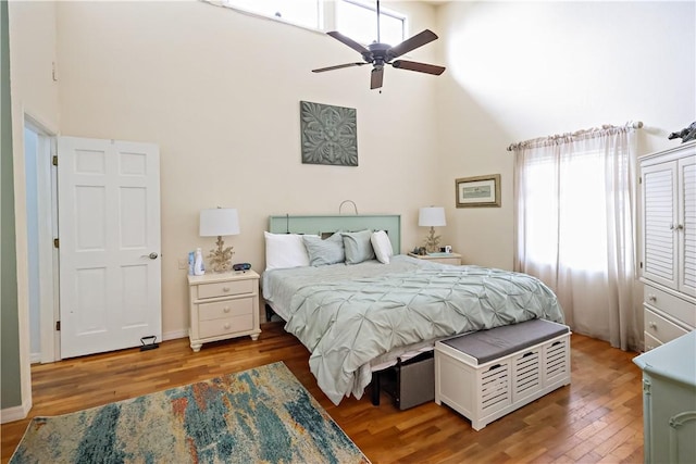 bedroom with hardwood / wood-style flooring, high vaulted ceiling, and ceiling fan