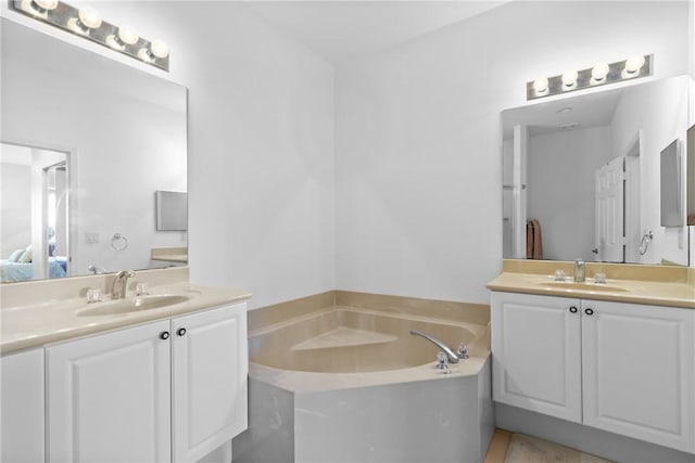 bathroom with a garden tub, two vanities, and a sink