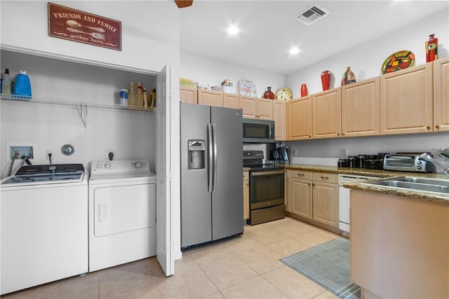 kitchen featuring light tile patterned floors, stainless steel appliances, visible vents, light brown cabinets, and independent washer and dryer