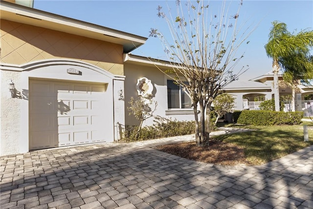 entrance to property with a garage and stucco siding