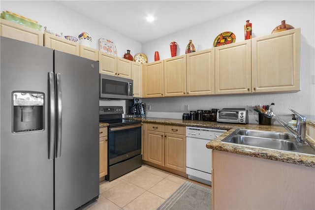 kitchen with light tile patterned floors, appliances with stainless steel finishes, a sink, and light brown cabinetry