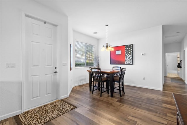 dining area with baseboards, dark wood-type flooring, and a notable chandelier