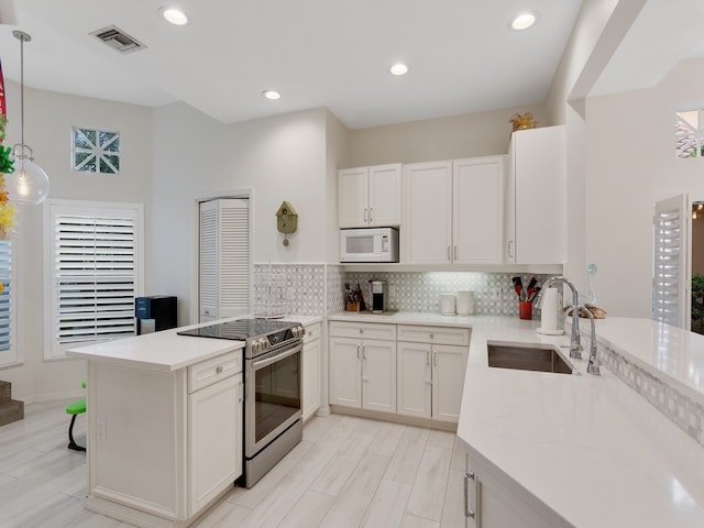 kitchen featuring white cabinets, sink, electric range, decorative light fixtures, and kitchen peninsula