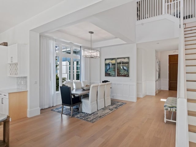 909 Surfsedge Way, Vero Beach, FL 32963 - dining space featuring stairway, light wood-style flooring, a chandelier, a raised ceiling, and a decorative wall