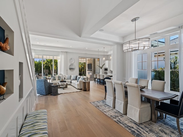 dining area featuring a tray ceiling, an inviting chandelier, and light wood-type flooring