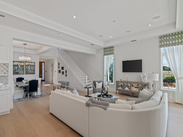 living room with a raised ceiling and light hardwood / wood-style flooring