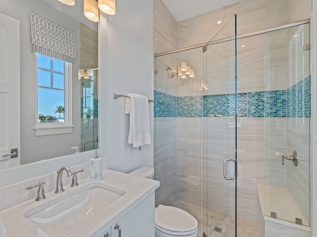 bathroom featuring vanity, a shower with shower door, and toilet