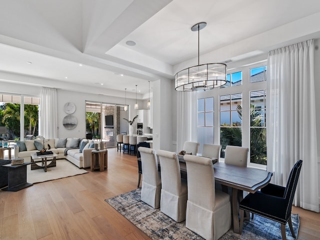 dining room featuring a tray ceiling, light hardwood / wood-style floors, and an inviting chandelier