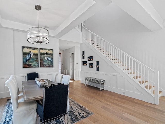 909 Surfsedge Way, Vero Beach, FL 32963 - dining room featuring light wood-style flooring, stairs, a chandelier, a decorative wall, and a wainscoted wall