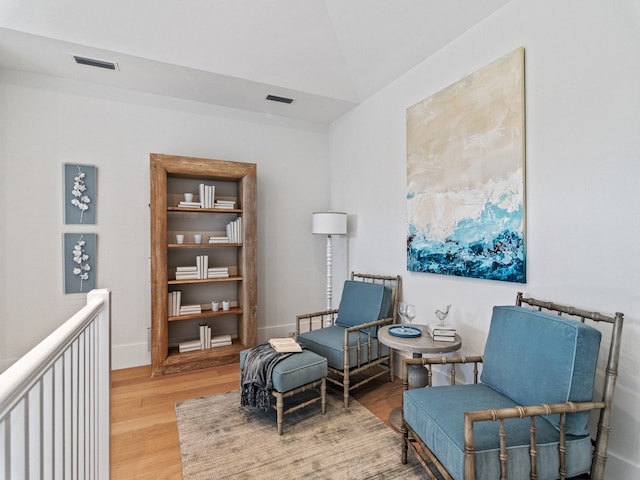 sitting room with hardwood / wood-style flooring and vaulted ceiling