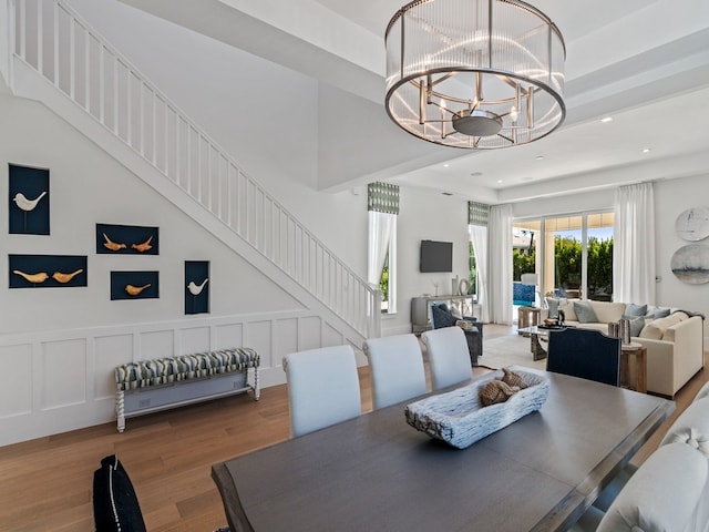 dining space featuring a towering ceiling, hardwood / wood-style flooring, and a notable chandelier