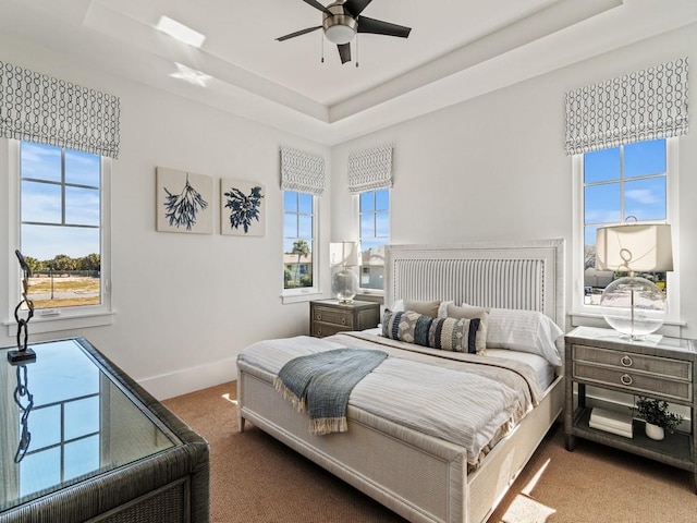 909 Surfsedge Way, Vero Beach, FL 32963 - carpeted bedroom featuring a tray ceiling, multiple windows, and ceiling fan