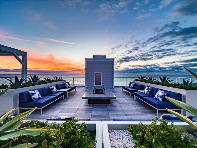 patio terrace at dusk with outdoor lounge area and a water view