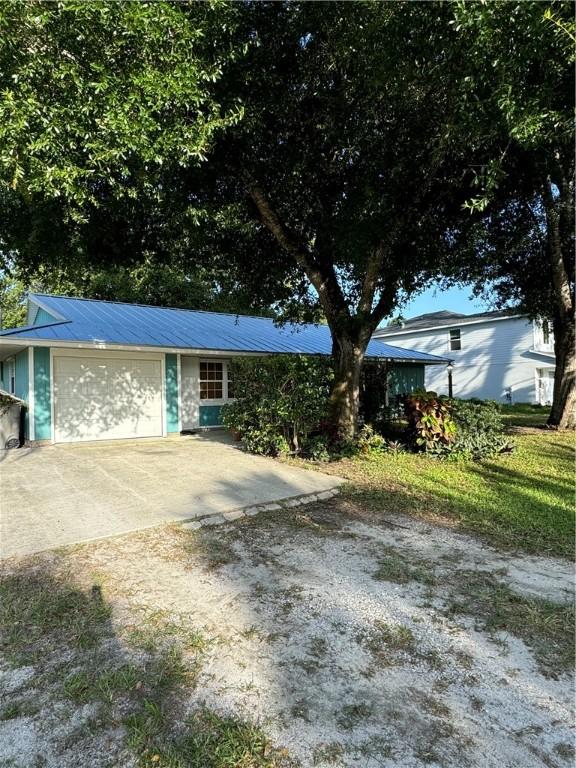 2380 89th Ave, Vero Beach, FL 32966 - ranch-style house featuring an attached garage, concrete driveway, and a metal roof