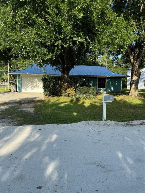 2380 89th Ave, Vero Beach, FL 32966 - view of front facade featuring a metal roof, a front yard, driveway, and an attached garage