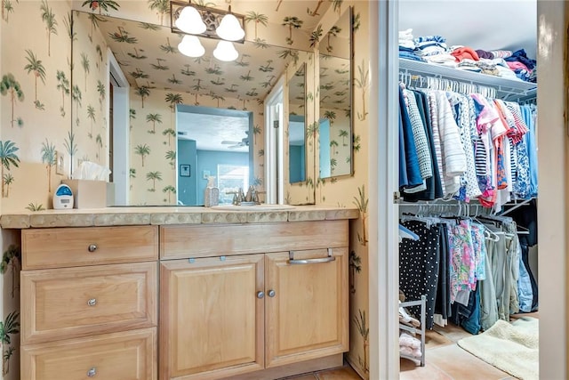 bathroom with a spacious closet, vanity, and wallpapered walls