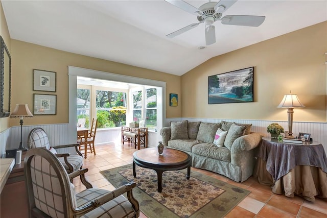 living room featuring a wainscoted wall, light tile patterned floors, and vaulted ceiling