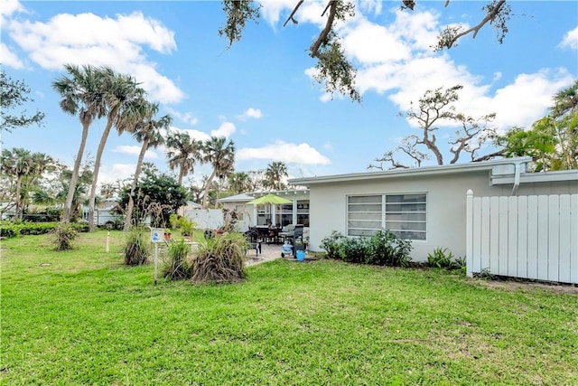 rear view of house with fence, a lawn, and a patio