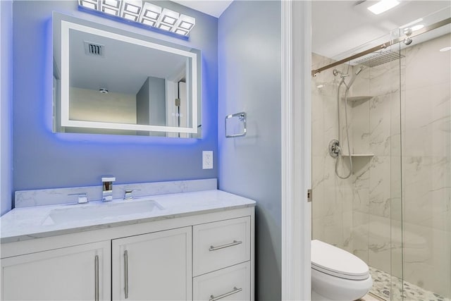 bathroom featuring toilet, visible vents, a marble finish shower, and vanity