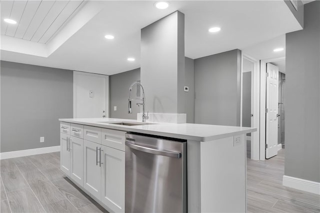 kitchen with a sink, light countertops, white cabinetry, baseboards, and stainless steel dishwasher