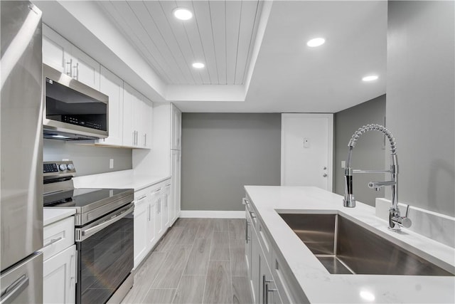 kitchen featuring recessed lighting, a sink, white cabinetry, and stainless steel appliances