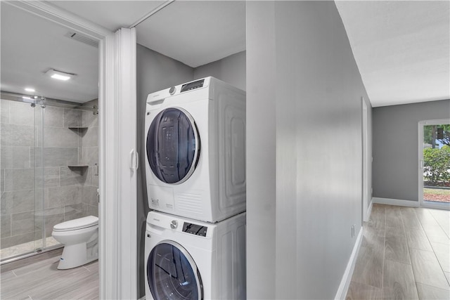 clothes washing area featuring baseboards, stacked washer / drying machine, and laundry area