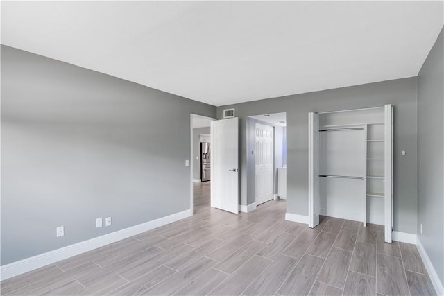 unfurnished bedroom featuring light wood-style floors, baseboards, a closet, and visible vents
