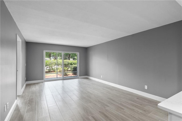 empty room with baseboards and light wood-style flooring