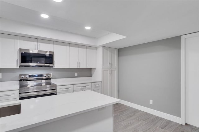 kitchen featuring baseboards, light countertops, white cabinetry, and stainless steel appliances