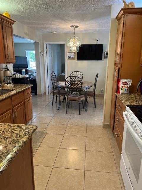 kitchen with a notable chandelier, a textured ceiling, light tile patterned floors, pendant lighting, and white electric stove