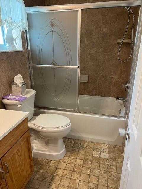 bathroom featuring vanity, toilet, and combined bath / shower with glass door
