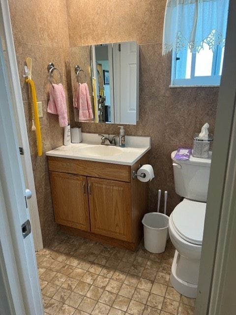 bathroom featuring tile walls, vanity, and toilet