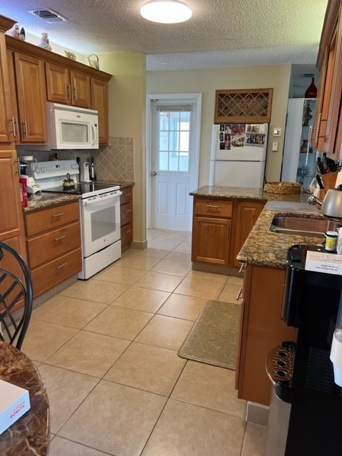 kitchen featuring light tile patterned floors, a textured ceiling, white appliances, and sink