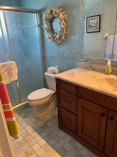 full bathroom featuring vanity, tile patterned flooring, a stall shower, and toilet