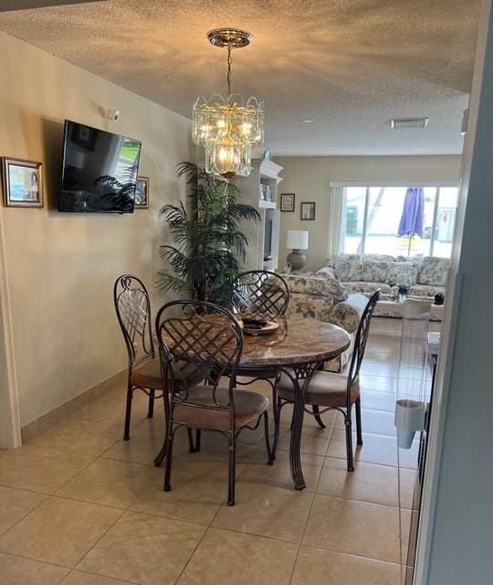 dining room featuring a textured ceiling, a chandelier, and light tile patterned flooring