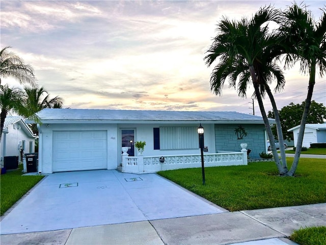 single story home with a garage, driveway, a yard, central AC, and stucco siding