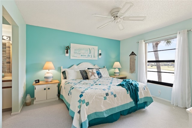 carpeted bedroom with a textured ceiling, ceiling fan, and ensuite bath