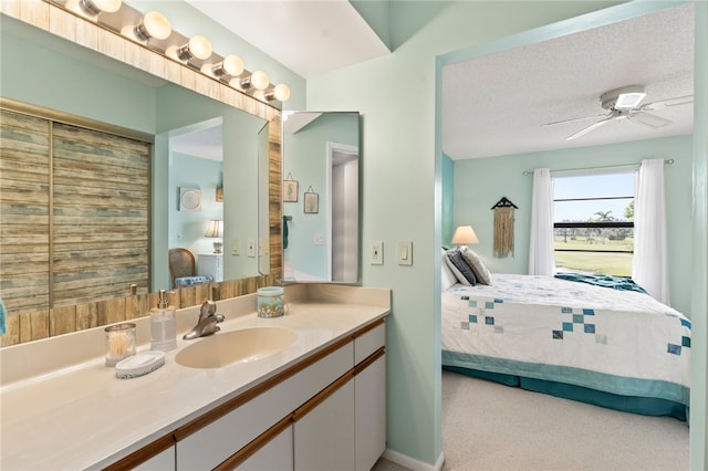 bathroom with ceiling fan, vanity, and a textured ceiling