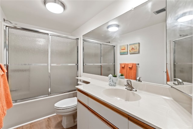 full bathroom featuring toilet, vanity, bath / shower combo with glass door, and hardwood / wood-style floors