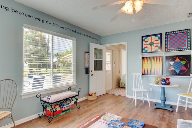 game room with a textured ceiling, hardwood / wood-style flooring, and ceiling fan