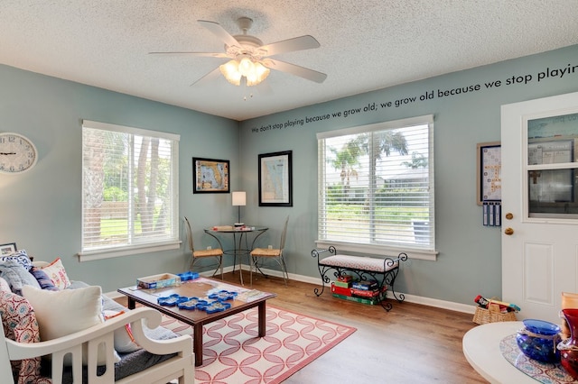 living room with hardwood / wood-style floors, ceiling fan, a textured ceiling, and a wealth of natural light