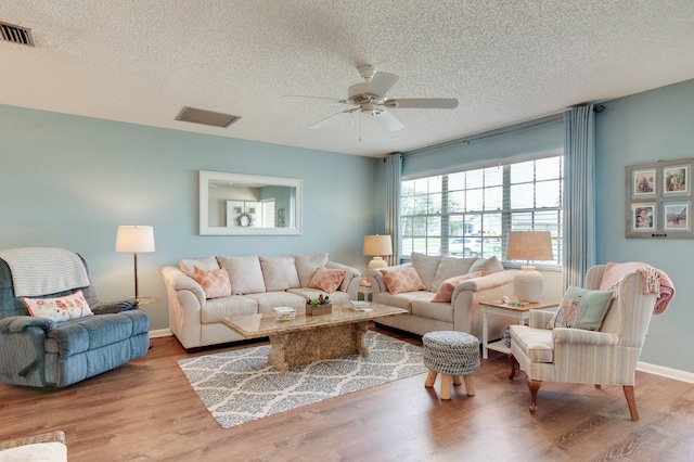 living room featuring ceiling fan, light hardwood / wood-style floors, and a textured ceiling