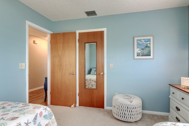 bedroom featuring light carpet and a textured ceiling