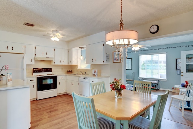 dining space featuring ceiling fan with notable chandelier, a textured ceiling, light hardwood / wood-style floors, and sink