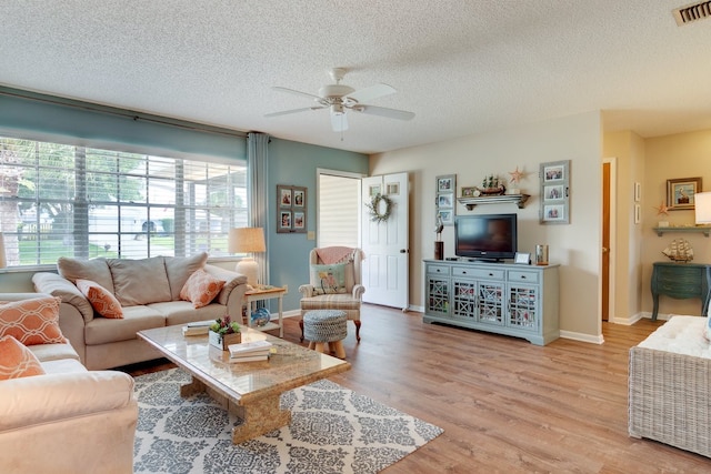 living room with a textured ceiling, light hardwood / wood-style floors, and ceiling fan