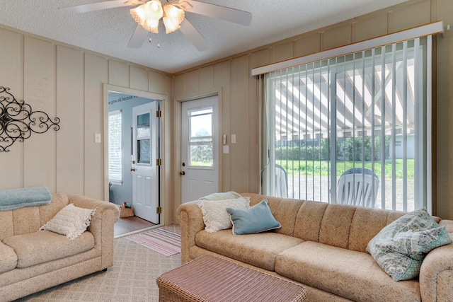 living room featuring ceiling fan and a textured ceiling