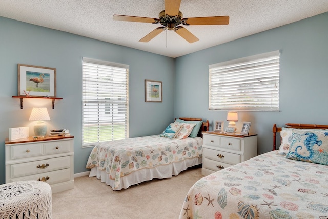 bedroom with a textured ceiling, light colored carpet, and ceiling fan