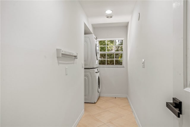 laundry area featuring stacked washer / drying machine and light tile patterned floors