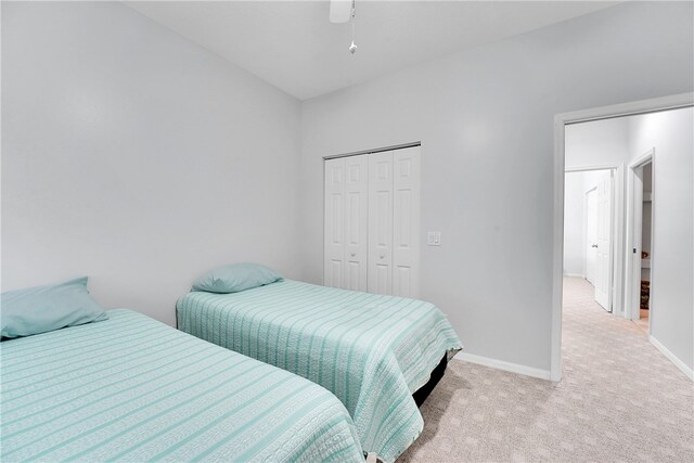 bedroom featuring ceiling fan, light carpet, and a closet