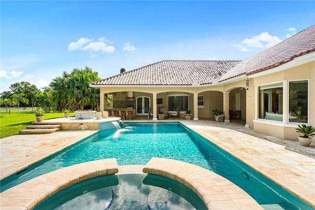 view of swimming pool featuring a patio area, pool water feature, and an in ground hot tub